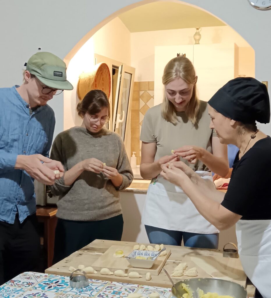 Vuoi imparare a preparare i culurgiones? Iscriviti al nostro corso di cucina in Ogliastra e scopri tutti i segreti di questa pasta tradizionale. Nella foto, alcuni dei nostri partecipanti all’opera, impegnati nella preparazione dei culurgiones in Ogliastra.